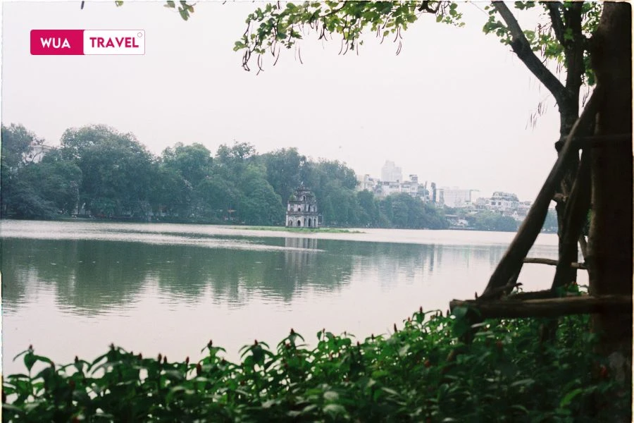 Hoan Kiem Lake in the morning, calm and serene, reflecting the peaceful start of a new day.